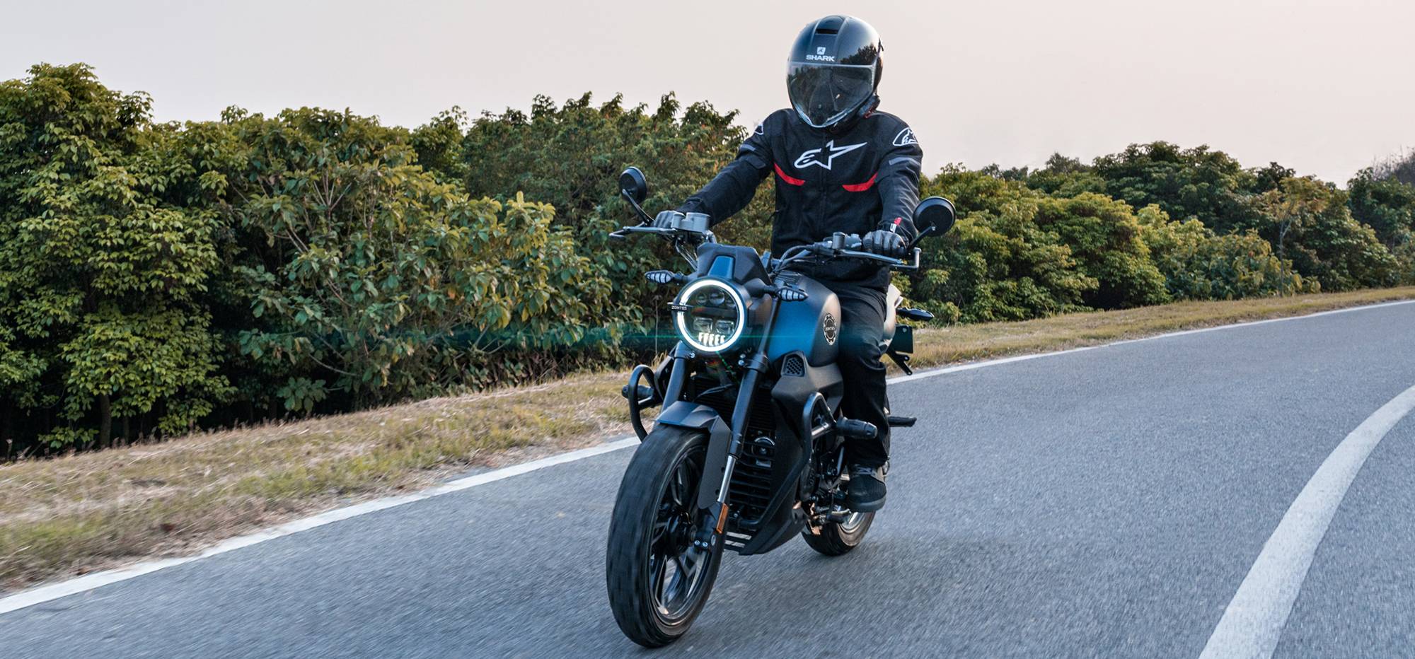 Zontes motos en Argentina - Moto Zontes 200G circulando con piloto de casco integral en una carretera abierta. Zontes motos en Argentina - Zontes 200G en marcha con conductor equipado sobre una ruta rodeada de vegetación.