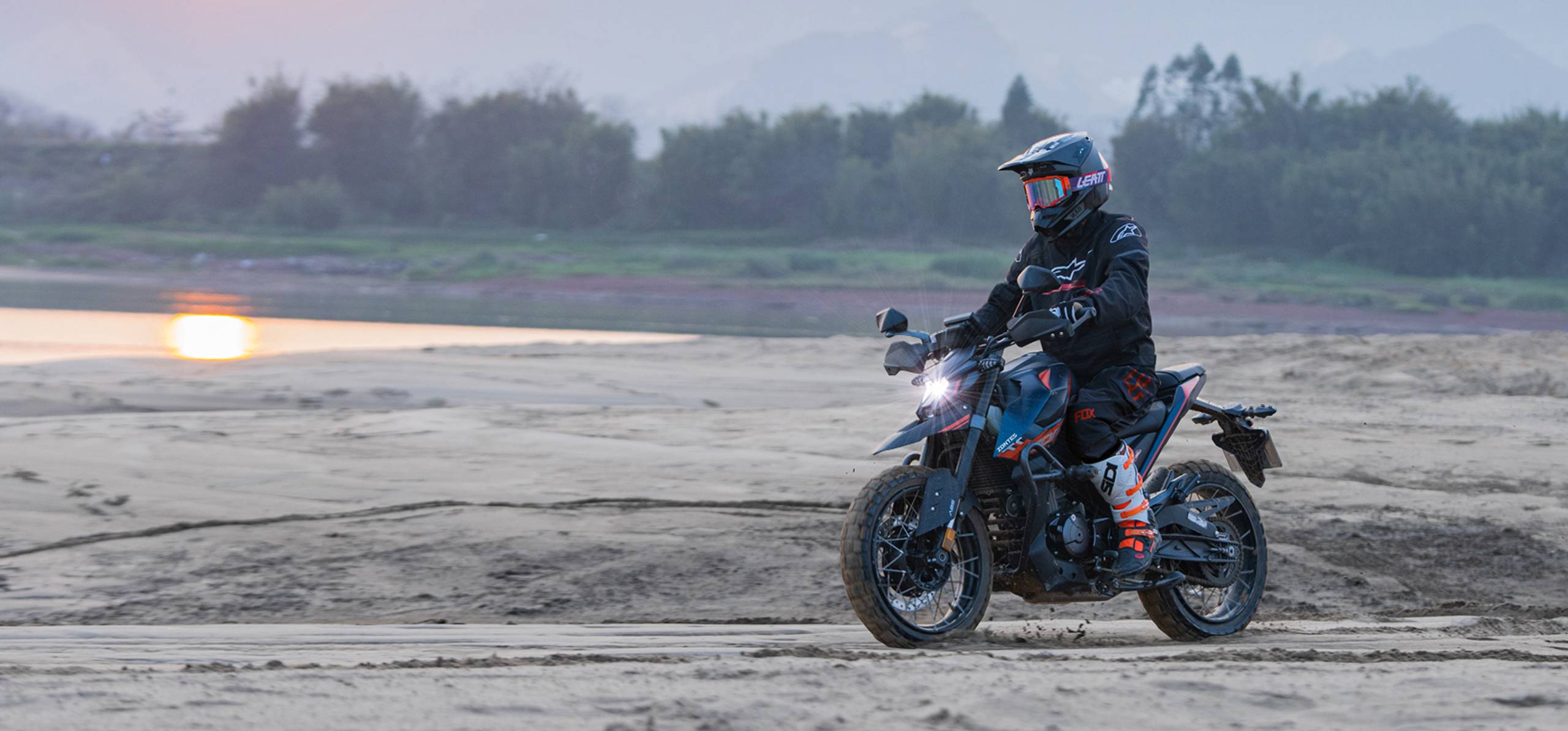 Zontes motos en Argentina - Moto Zontes 200U circulando sobre terreno de arena con piloto de casco y equipamiento offroad. Zontes motos en Argentina - Zontes 200U en marcha sobre arena con conductor equipado y faro delantero encendido.
