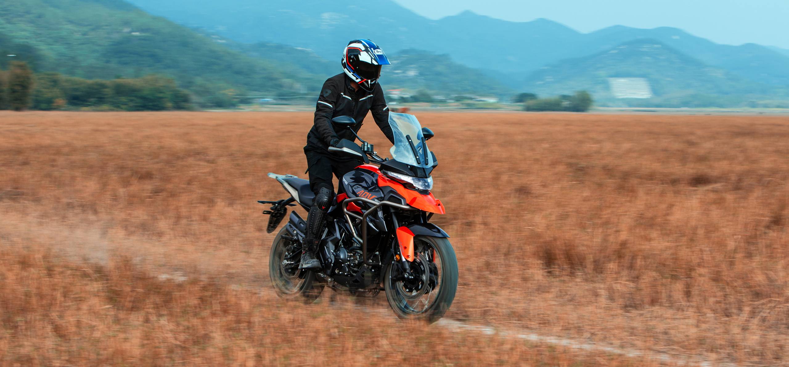 Zontes motos en Argentina - Zontes 350T en movimiento sobre terreno seco Zontes motos en Argentina - Piloto conduciendo una Zontes 350T naranja y negra por un campo seco, vista frontal derecha en movimiento.