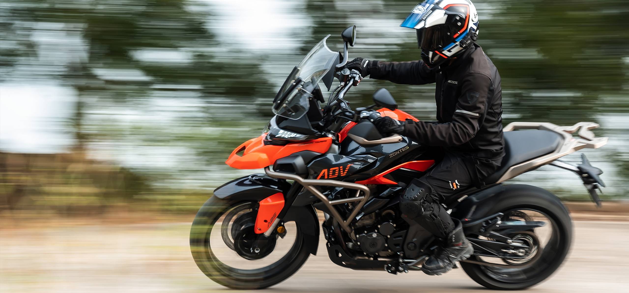 Zontes motos en Argentina - Zontes 350T lateral derecha en movimiento Zontes motos en Argentina - Piloto sobre Zontes 350T naranja y negra en movimiento lateral derecho, con fondo barrido y sensación de velocidad.