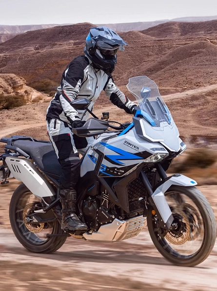 Zontes motos en Argentina - Zontes 703F en camino de tierra con conductor equipado y paisaje árido de fondo.