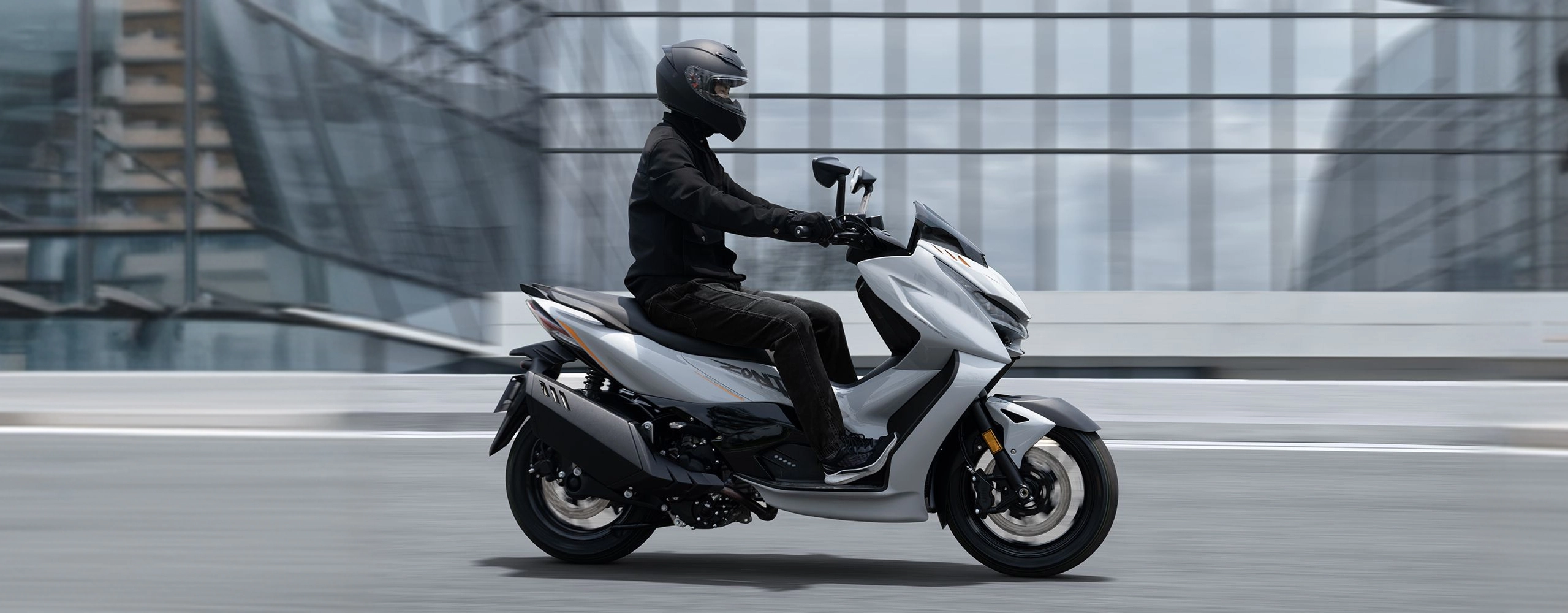 Zontes motos en Argentina - Scooter 368D circulando en ciudad con conductor, carroceria clara y postura de manejo relajada. Zontes motos en Argentina - Zontes 368D gris claro en movimiento con conductor equipado sobre una avenida entre edificios modernos.