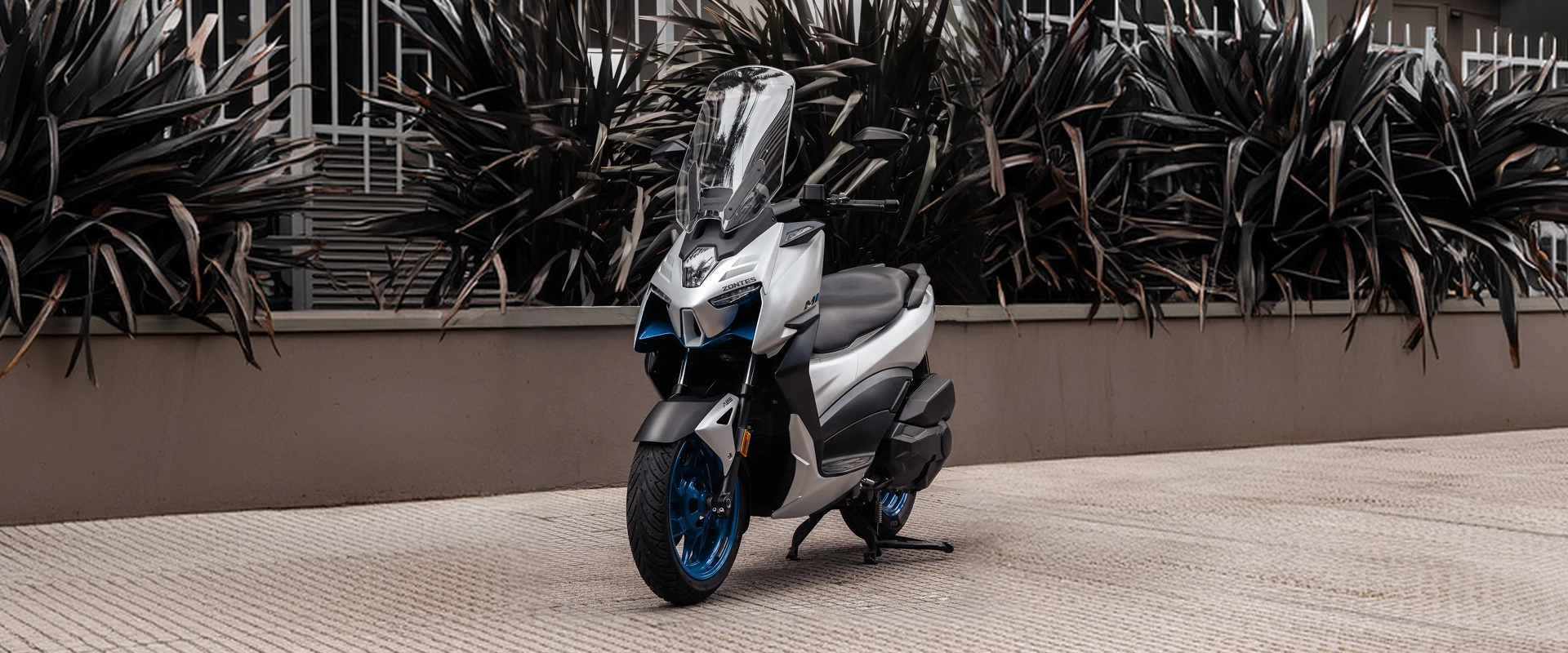Zontes motos Argentina - Zontes 368M blanco con frente alto Zontes motos Argentina - scooter Zontes 368M blanco estacionado frente a plantas oscuras