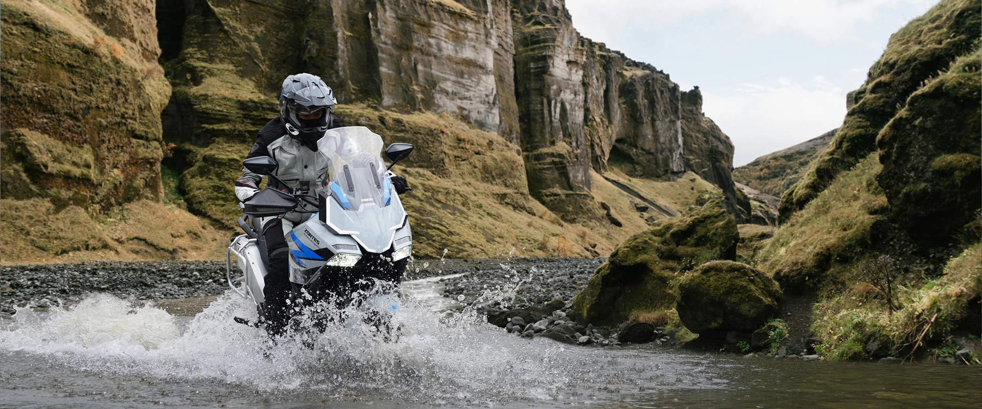 Zontes motos Argentina - Zontes 703F en recorrido de aventura Zontes motos Argentina - moto Zontes 703F blanca atravesando agua con conductor equipado entre formaciones rocosas